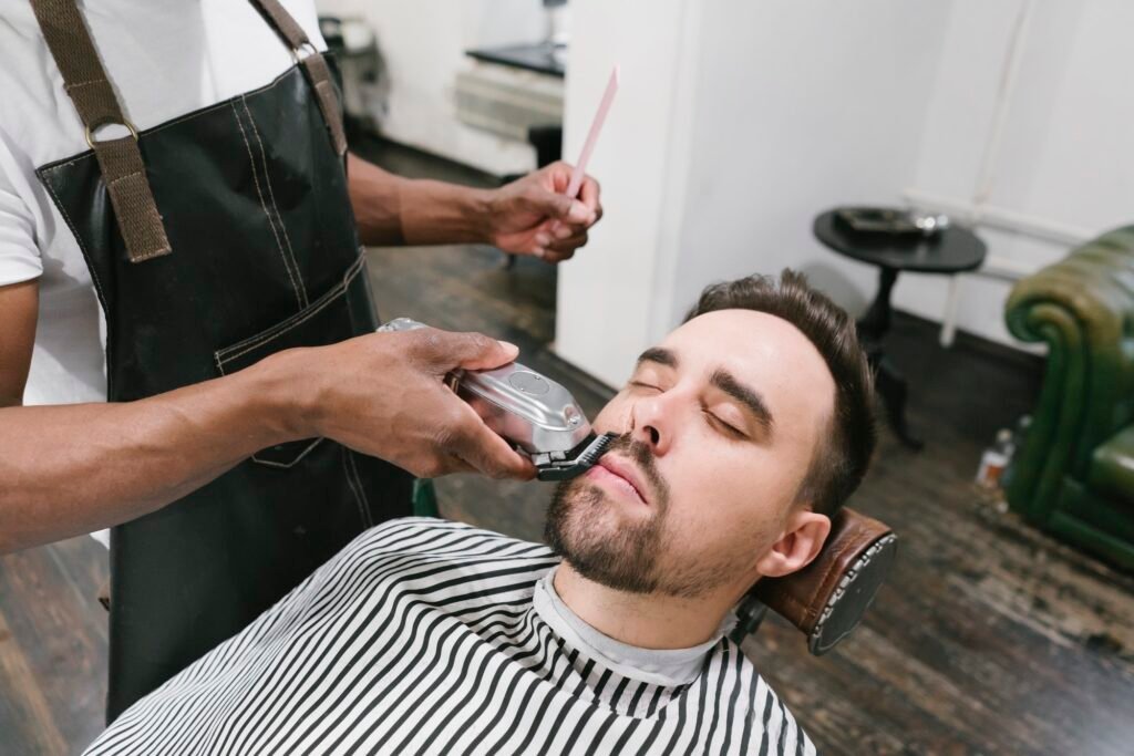 Barber cutting beard of a customer in barber shop